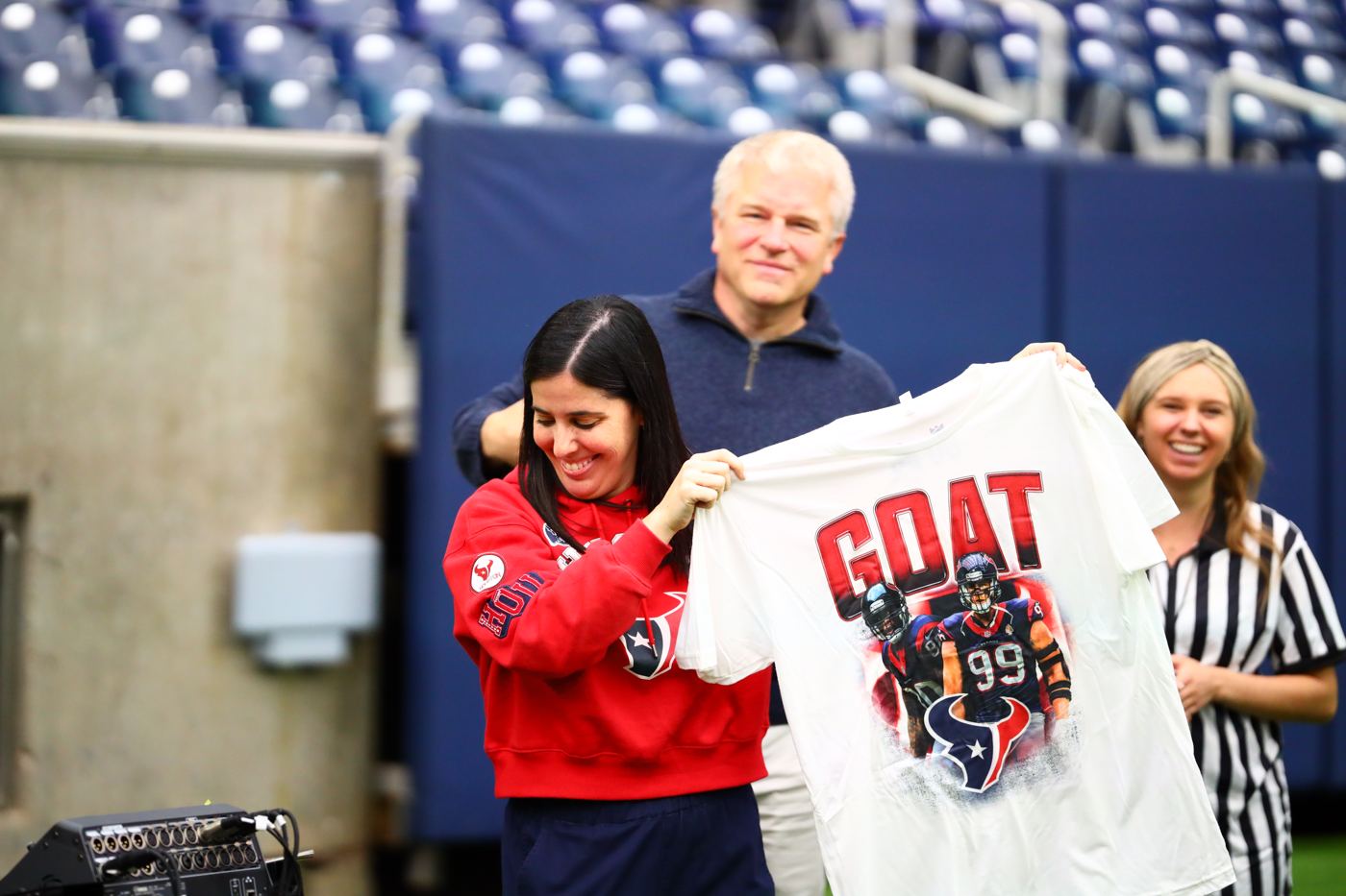 Lindsey Fox laughing as she holds up a GOAT t-shirt on the field during a team event